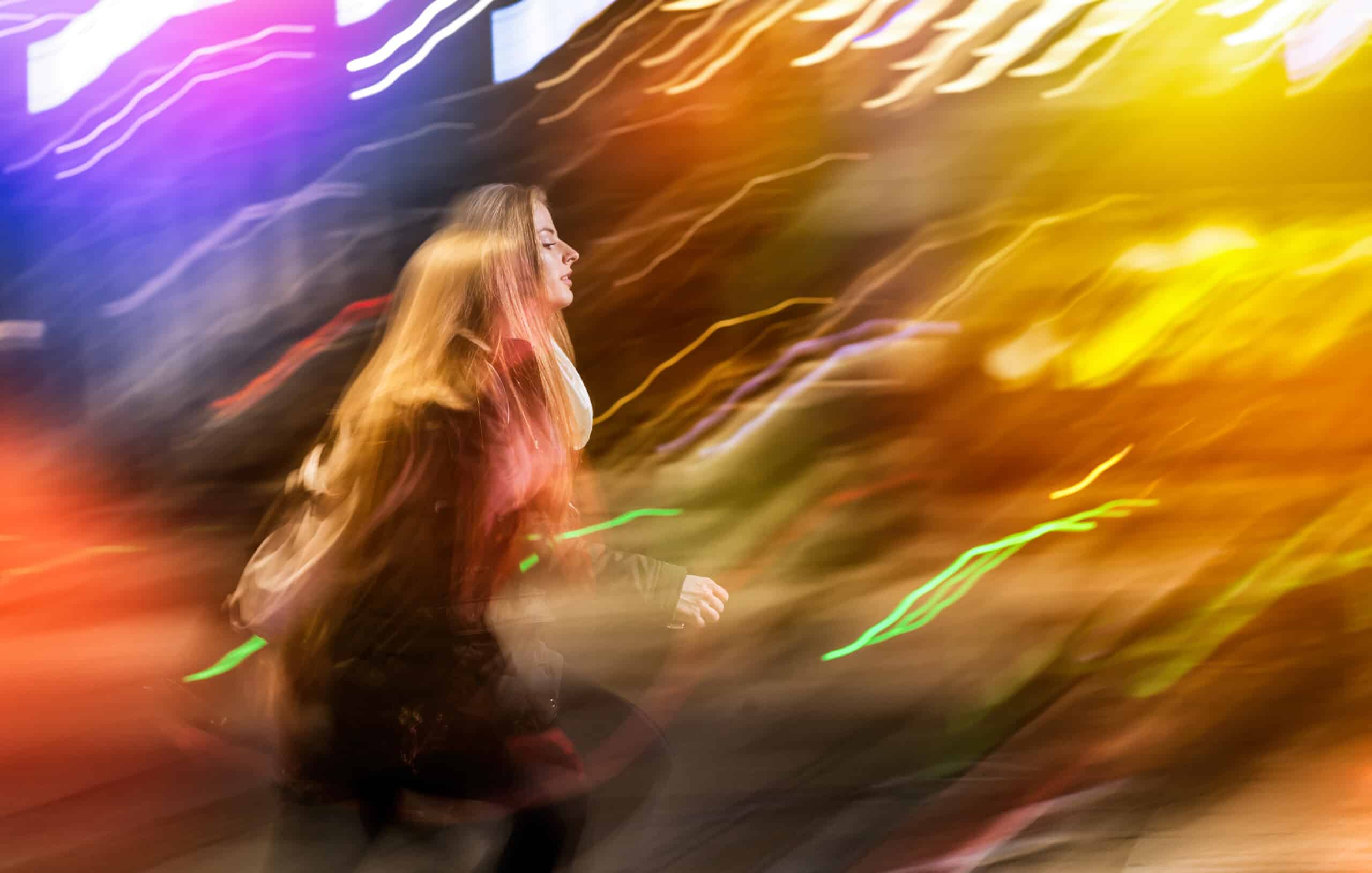 Woman in city at night among neon moving lights